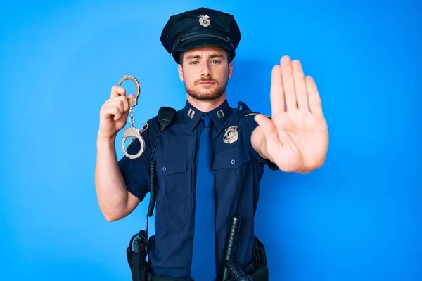 Молодий Білий Чоловік Поліцейській Формі Тримає Наручники Відкритою Рукою Робить — стокове фото