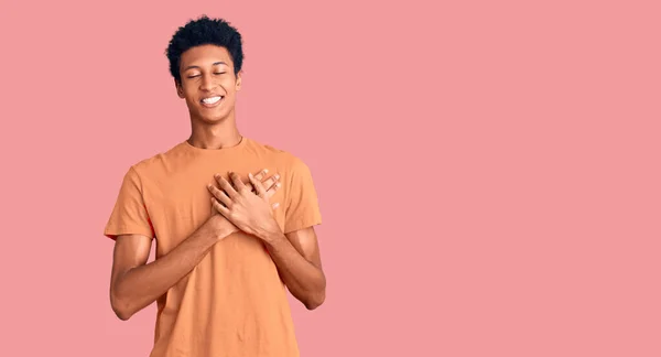 年轻的非洲裔美国人 身穿休闲装 双手胸前挂着微笑 闭着眼睛 脸上挂着感激的手势 健康概念 — 图库照片