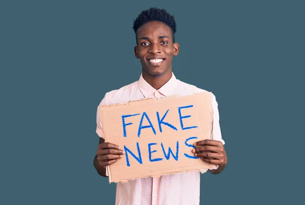 Młody Afrykanin Amerykański Mężczyzna Trzyma Fałszywy Baner Wiadomości Patrząc Pozytywnie — Zdjęcie stockowe