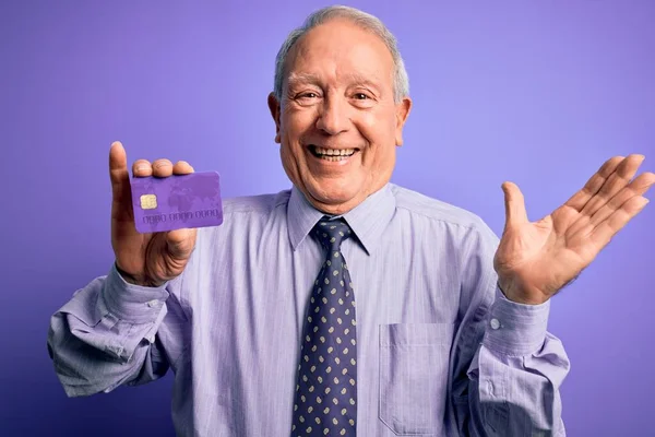 Senior Gråhårig Affärsman Håller Kreditkort Över Lila Bakgrund Mycket Glad — Stockfoto