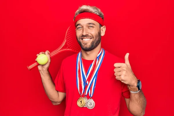 毛深いですブロンドスポーツマンとともにひげ賞を受賞したメダルプレイテニスを使用してラケットとボール笑顔幸せと正 親指アップ行う優れた承認サイン — ストック写真