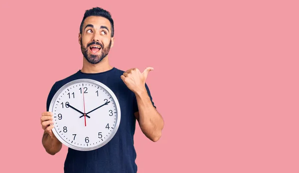 Giovane Uomo Ispanico Tenendo Grande Orologio Puntando Pollice Verso Alto — Foto Stock