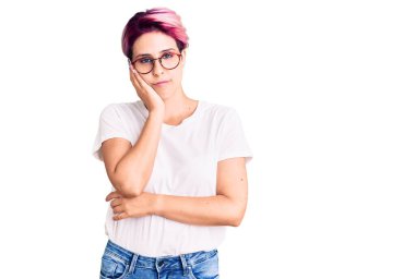 Pembe saçlı, günlük kıyafetler giyen ve gözlüklü genç bir kadın kollarını kavuşturarak depresyondan sıkılmış ve yorgun göründüğünü düşünüyor.. 