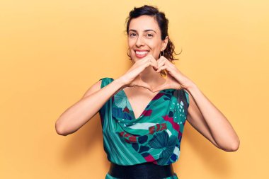 Gündelik kıyafetler giyen, aşık gülümseyen, elleriyle kalp sembolü yapan genç, güzel İspanyol bir kadın. romantik kavram. 