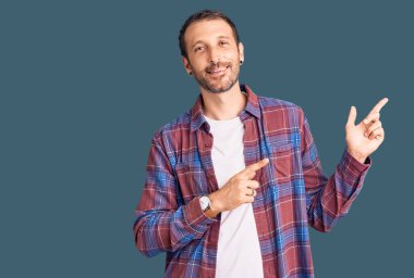 Gündelik kıyafetler giyen, gülümseyen ve kameraya bakan genç, yakışıklı bir adam.. 