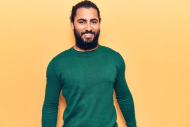 Yüzünde mutlu ve havalı bir gülümseme olan sıradan kıyafetler giyen genç bir Arap. şanslı kişi. 