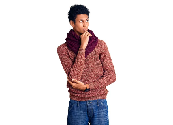 カジュアルな冬のセーターとスカーフを身に着けている若いアフリカ系アメリカ人の男性は 集中的な表現について考えています 思慮深い顔で笑顔 疑わしい概念 — ストック写真