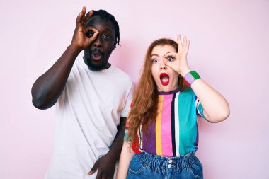 Irklar arası giyinmiş, normal bir jest yapan, şaşkın suratlı, gözleriyle parmaklarından bakan bir çift. İnançsız ifade. 