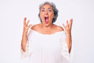 Son sınıf Latin kökenli, gri saçlı, günlük kıyafetler giyen çılgın ve kızgın bir kadın. Saldırgan bir ifadeyle bağırıyor ve kollarını kaldırıyor. hüsran kavramı. 