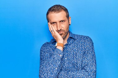 Gündelik kıyafetler giyen yakışıklı genç adam kollarını kavuşturarak depresyondan sıkılmış ve yorgun görünüyor.. 