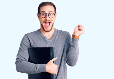 Genç, yakışıklı, beyaz bir adam iş dosyasını tutuyor. Gururla bağırıyor, zaferi ve başarıyı kutluyor. Kollarını kaldırarak heyecanlanıyor. 