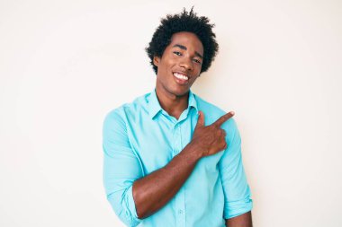 Yakışıklı afro saçlı, neşeli giyinen, yüzünde mutlu ve doğal bir ifadeyle elleri ve parmaklarıyla yüzünü gösteren yüzü olan Afro-Amerikan erkeği. 