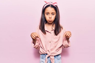 Güzel bir kız çocuğu günlük giysiler içinde üzgün ve üzgün görünüyor, parmaklarıyla yön gösteriyor, mutsuz ve depresif.. 