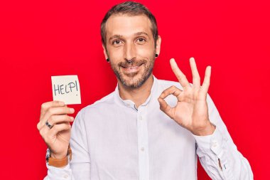 Genç yakışıklı adam hatırlatıcı tutuyor. Parmaklarınla imzala, gülümse. Dostça hareketler yap. Mükemmel bir sembol. 