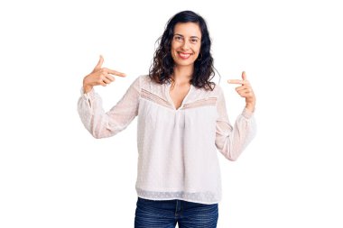 Genç ve güzel İspanyol kadın gündelik kıyafetler giyiyor. Kendine güveniyor gibi görünüyor. Yüzünde gülücüklerle kendini gururlu ve mutlu olarak gösteriyor.. 