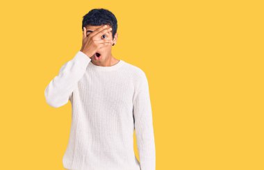 Genç Afro-Amerikan bir adam günlük giysiler giymiş. Şoka girmiş, yüzünü ve gözlerini kapamış, utanmış bir ifadeyle parmaklarından bakıyor.. 