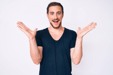 Gündelik kıyafetler giyen genç yakışıklı adam zaferi mutlu bir gülümsemeyle ve kazanan yüz ifadesiyle kutluyor. 