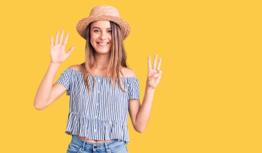 Şapka ve tişört giyen genç ve güzel bir kız sekiz numaralı parmaklarını gösterip gösterirken kendinden emin ve mutlu bir şekilde gülümsüyor.. 