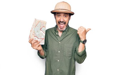 Gezgin şapkası takmış, elinde şehir haritasıyla gezen orta yaşlı, yakışıklı bir turist. Başparmağıyla yan tarafa bakıyor, ağzı açık gülümsüyor.