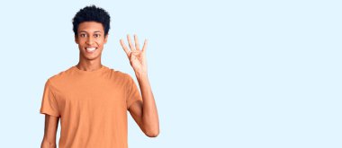 Genç Afro-Amerikalı günlük kıyafetler giymiş dört numarayı gösterip işaret ederken kendinden emin ve mutlu bir şekilde gülümsüyor.. 