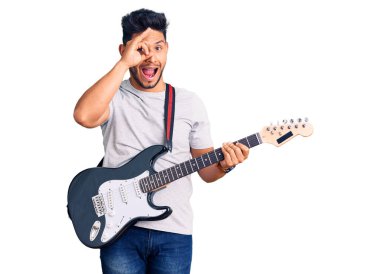 Yakışıklı Latin Amerikalı genç adam elektro gitar çalarken gülümsüyor. Mutluluktan gülümsüyor. 