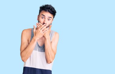 Gündelik kıyafetler giyen genç İspanyol adam yanlışlıkla elleri ile ağzını kapatırken şok oldu. gizli kavram. 