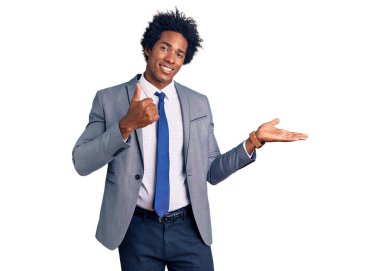 Yakışıklı Afro saçlı, iş ceketi giyen, el hareketi yapan, mutlu ve neşeli gülümseyen Afro-Amerikan erkeği. 