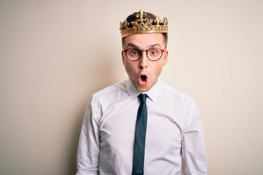 Kafkasyalı yakışıklı iş adamı, izole edilmiş arka planda altın taç takıyor. Şaşırmış ve korkmuş bir ifade, korku ve heyecanlı bir yüz..
