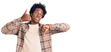 Afro saçlı, sıradan kıyafetler giyen ve gözlüklü, baş parmak hareketi yapan, anlaşmazlık ve uzlaşma ifadesi olan yakışıklı Afro-Amerikan bir adam. çılgın çatışma 