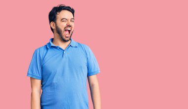 Gündelik kıyafetler giyen genç İspanyol adam kameraya seksi bir ifadeyle bakıyor, neşeli ve mutlu bir yüzle.. 