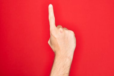 Kafkas genci parmaklarını izole edilmiş kırmızı arka planda gösteriyor. İşaret parmağı kullanarak bir numarayı sayıyor. Fikir ve anlayış gösteriyor.