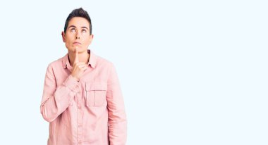 Kısa saçlı, günlük kıyafetler giyen, şüpheye odaklanmış, çenesinde parmak olan ve kafasını kaldırıp merak eden genç bir kadın. 