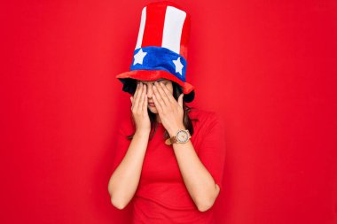 Amerika Birleşik Devletleri şapkası takan genç güzel esmer kadın bağımsızlık gününü kutluyor yorgunluk ve baş ağrısı için gözlerini ovuşturuyor, uykulu ve yorgun bir ifade takınıyor. Görüş sorunu