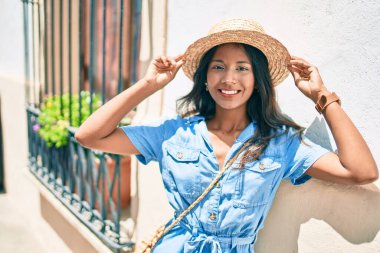 Genç, güzel Hintli bir kadın duvara yaslanıyor ve gülümsüyor..