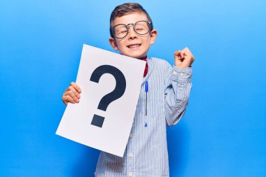 Sevimli sarışın çocuk inek papyonu ve gözlük takıyor. Elinde soru işareti var. Gururla bağırıyor, zaferi kutluyor ve başarıyı kollarını kaldırarak kutluyor. 