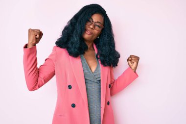 İş ceketi ve gözlük takan güzel Afrikalı kadın gururla gülümseyen kol kaslarını gösteriyor. fitness konsepti. 