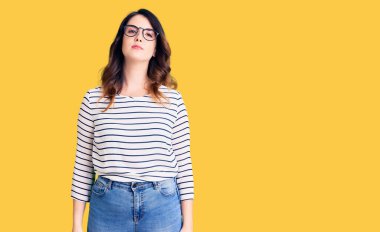 Gündelik kıyafetler ve gözlük takan güzel, genç esmer kadın yüzünde ciddi bir ifadeyle rahatlamış. Basit ve doğal bir şekilde kameraya bakıyorsun.. 