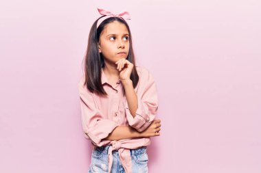 Güzel bir kız çocuğu. Elleri çenesinde gündelik giysiler giyip soru soruyor. Düşünceli bir ifade takınıyor. Düşünceli bir yüzle gülümsüyor. şüphe kavramı. 