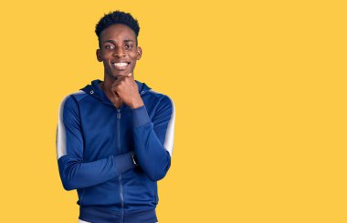 Afrikalı genç bir Amerikalı spor giyer kameraya bakar kollarını kavuşturup gülümser ve çenesini kaldırır. Olumlu düşünmek. 