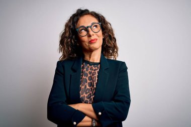 Orta yaşlı esmer iş kadını gözlüklü, izole edilmiş beyaz arka planda durup gülümseyen ve kafasını çeviren..