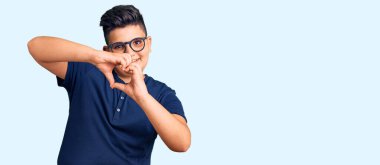 Gündelik giysiler ve gözlük takan, aşık gülümseyen küçük çocuk elleriyle kalp sembolü yapıyor. romantik kavram. 