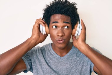 Yakışıklı Afro saçlı, müzik dinleyen kulaklık takan, gülümseyen ve kafasını çeviren afro-amerikalı adam.. 