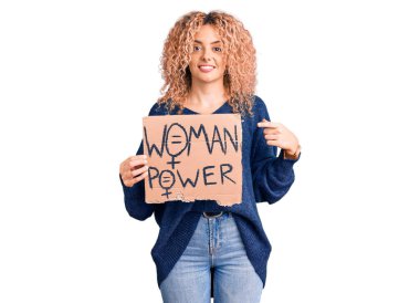 Sarışın, kıvırcık saçlı genç bir kadın. Değişim afişine ihtiyacımız var. Gülümseyen mutlu bir el ve parmak işaretine. 