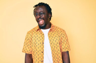 Saçları örgülü genç Afro-Amerikalı adam kameraya seksi bir ifadeyle bakıyor, neşeli ve mutlu bir yüzle.. 