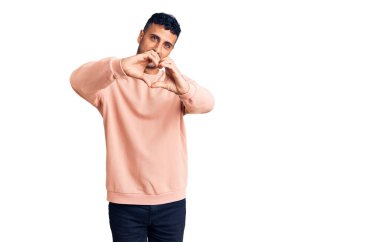 Gündelik kıyafetler giyen, aşık gülümseyen, elleriyle kalp sembolü yapan genç bir İspanyol. romantik kavram. 