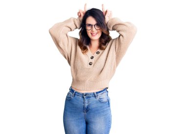 Güzel, genç, esmer bir kadın. Günlük kıyafetler ve gözlük takıyor. Komik jestler yapıyor. 