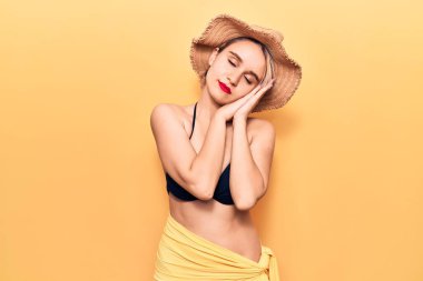 Bikini ve yaz şapkası takan güzel sarışın kadın yorgun uyuyor, hayal kuruyor ve ellerimizle poz veriyor, gözleri kapalı gülümsüyor.. 