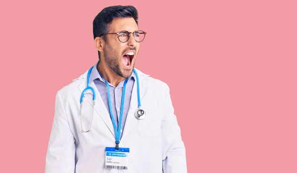 Joven Hispano Vistiendo Uniforme Médico Estetoscopio Enojado Loco Gritando Frustrado —  Fotos de Stock