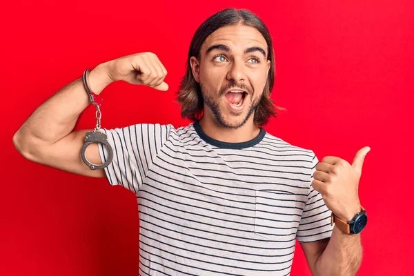 Junger Gutaussehender Mann Gefangenenhandschellen Der Den Daumen Zur Seite Zeigt — Stockfoto