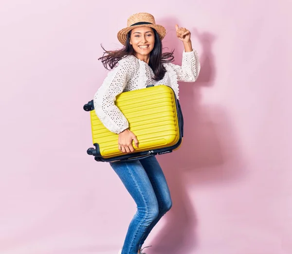 夏服を着て休暇中の若い美しい女性と帽子幸せな笑顔 顔に笑顔でジャンプ隔離された背景にキャビンバッグを保持 — ストック写真